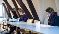 Drie personen die aan lange tafel documenten doornemen
