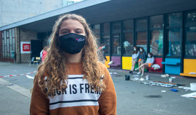 Aspimeisje met mondmasker poseert voor groep