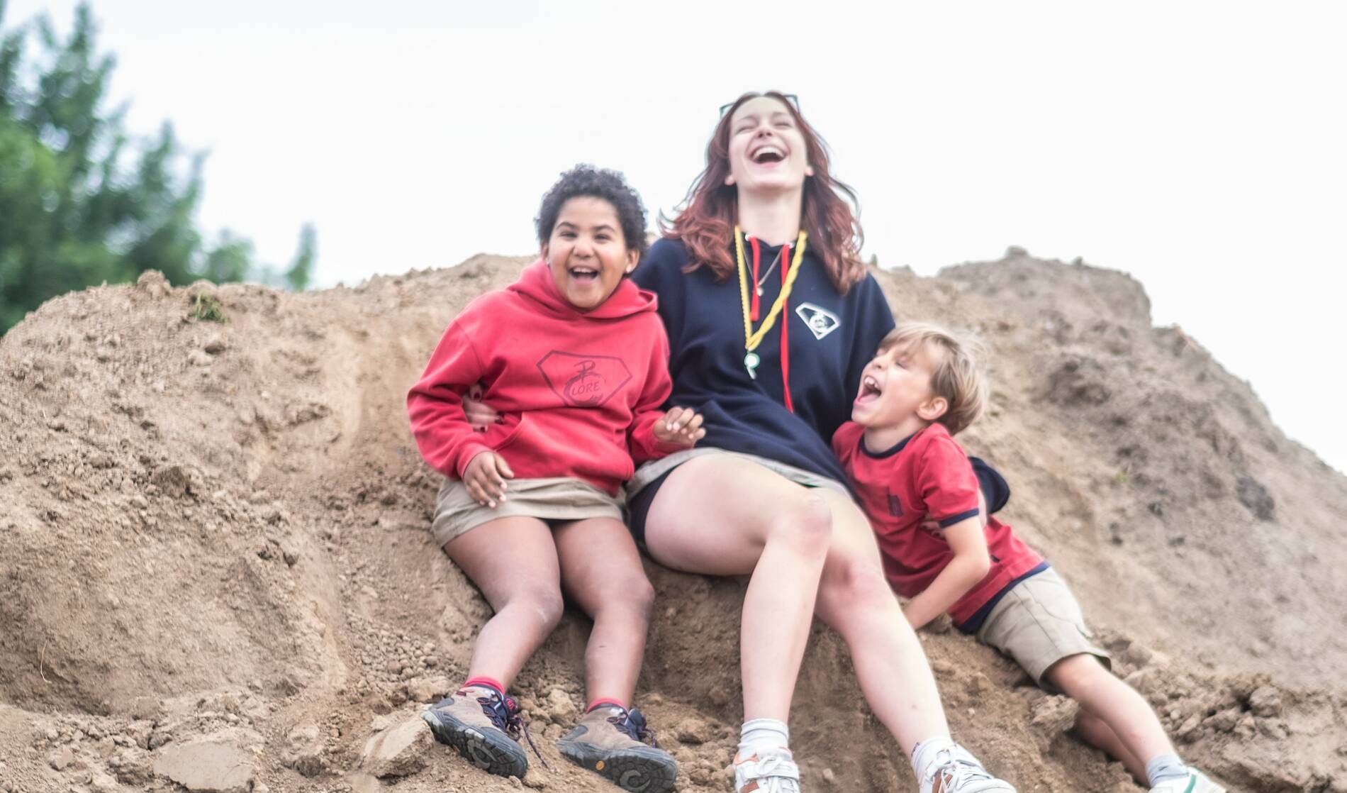 Chiroleidster speelt met kinderen op berg zand