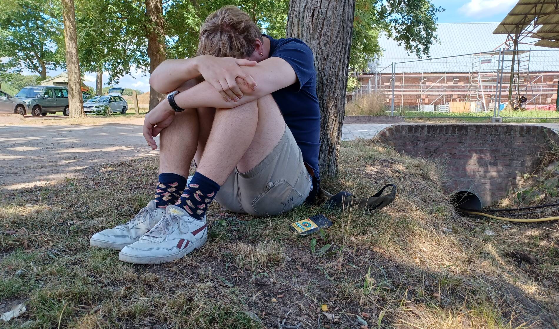 Trieste jongen zit eenzaam tegen boom