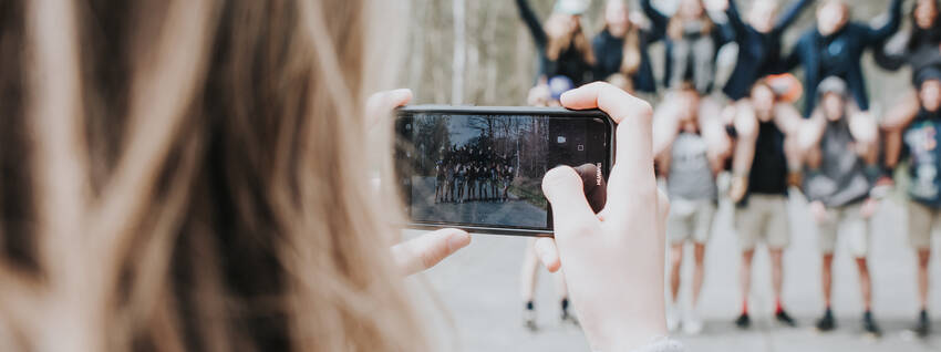 Een Chiroleidster neemt met haar gsm een foto van Chiroleden