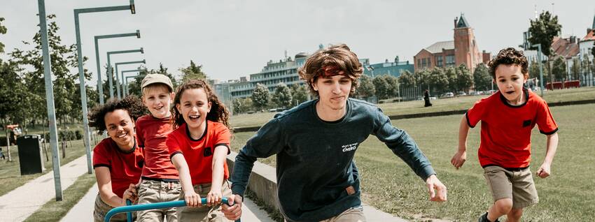 De foto die op de voorpagina van de beleidsnota 2022-2025 staat. Verschillende kinderen en jongeren lopen samen richting de camera. 