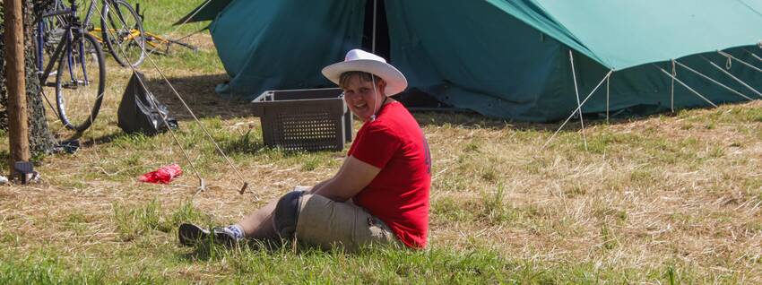 Jongen zit op de grond voor een tent
