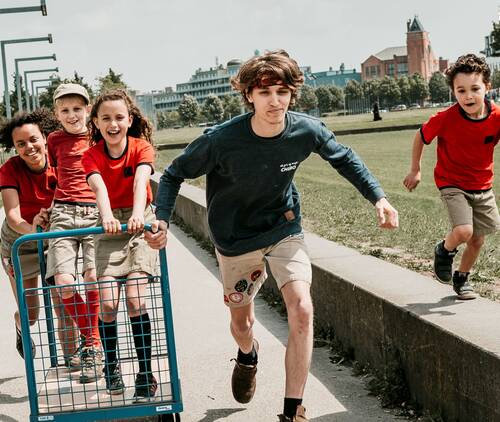 De foto die op de voorpagina van de beleidsnota 2022-2025 staat. Verschillende kinderen en jongeren lopen samen richting de camera. 